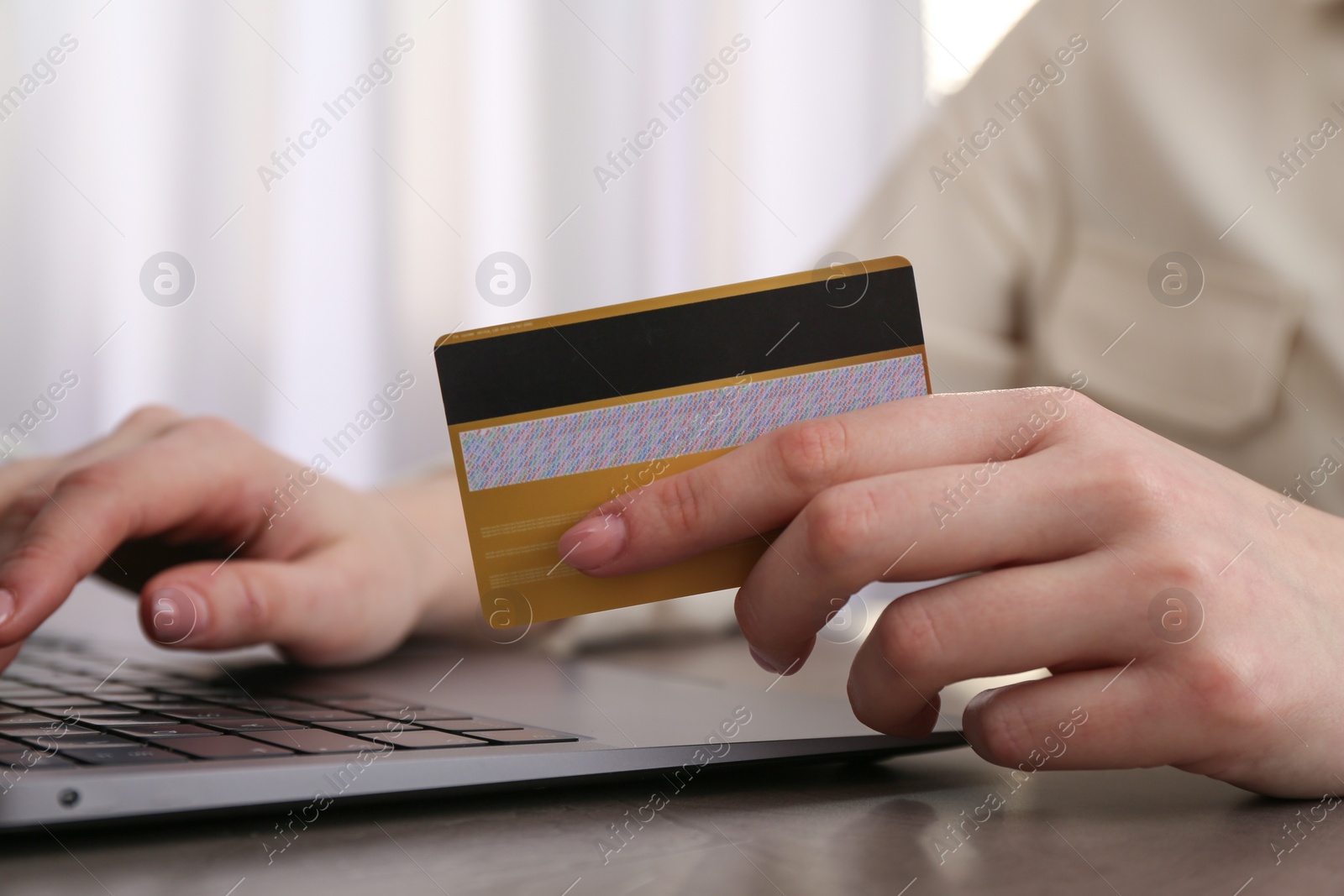 Photo of Online payment. Woman with laptop and credit card at grey table, closeup