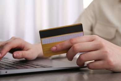 Photo of Online payment. Woman with laptop and credit card at grey table, closeup