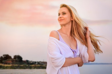 Beautiful young woman on beach in evening, space for text