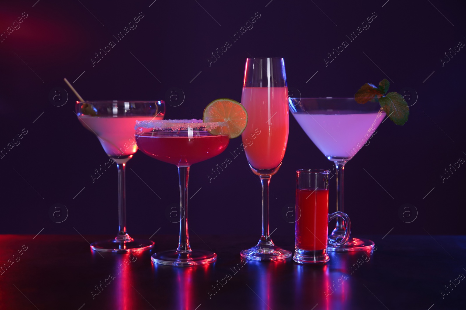 Photo of Many different alcoholic drinks on table against dark background