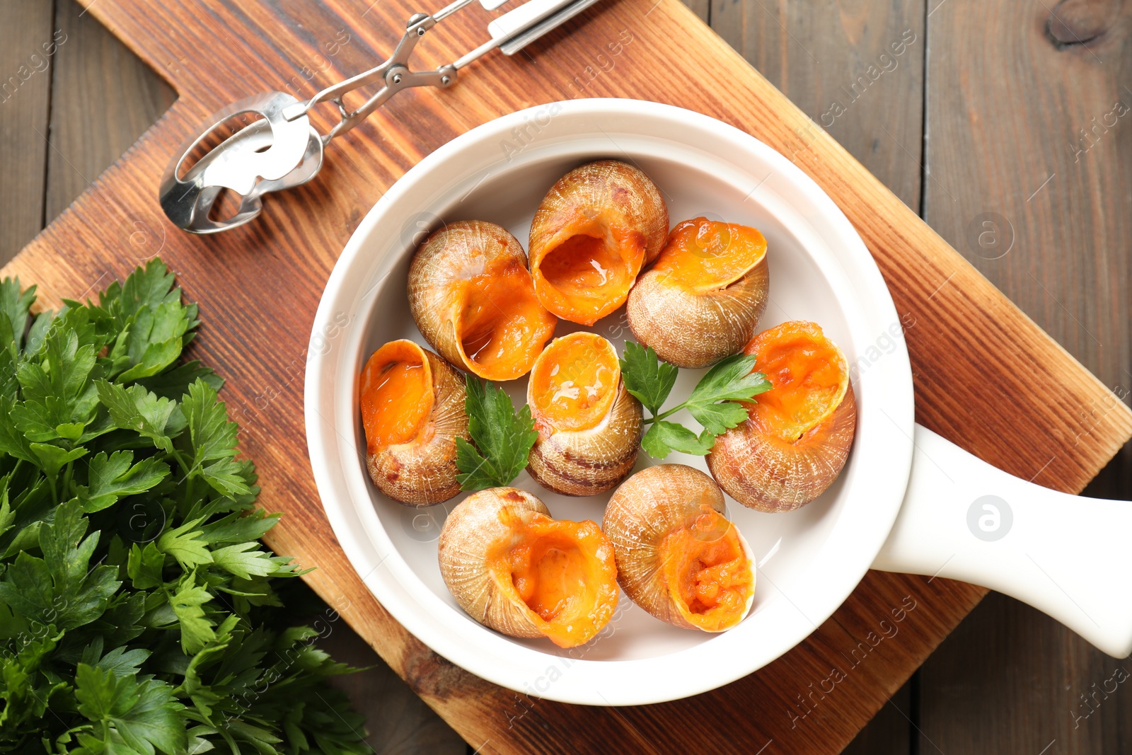 Photo of Delicious cooked snails served on wooden table, flat lay