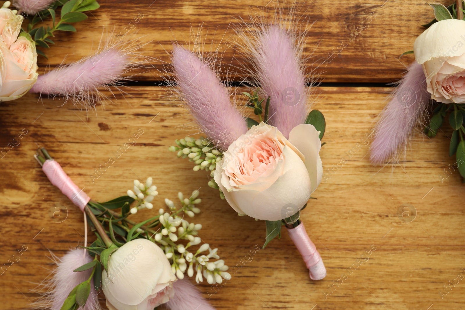 Photo of Many stylish boutonnieres on wooden table, flat lay