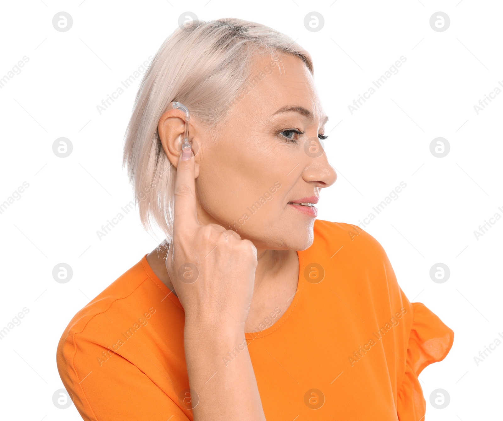 Photo of Mature woman adjusting hearing aid on white background