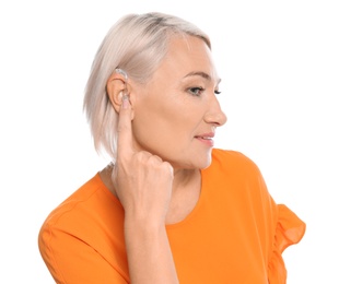 Mature woman adjusting hearing aid on white background