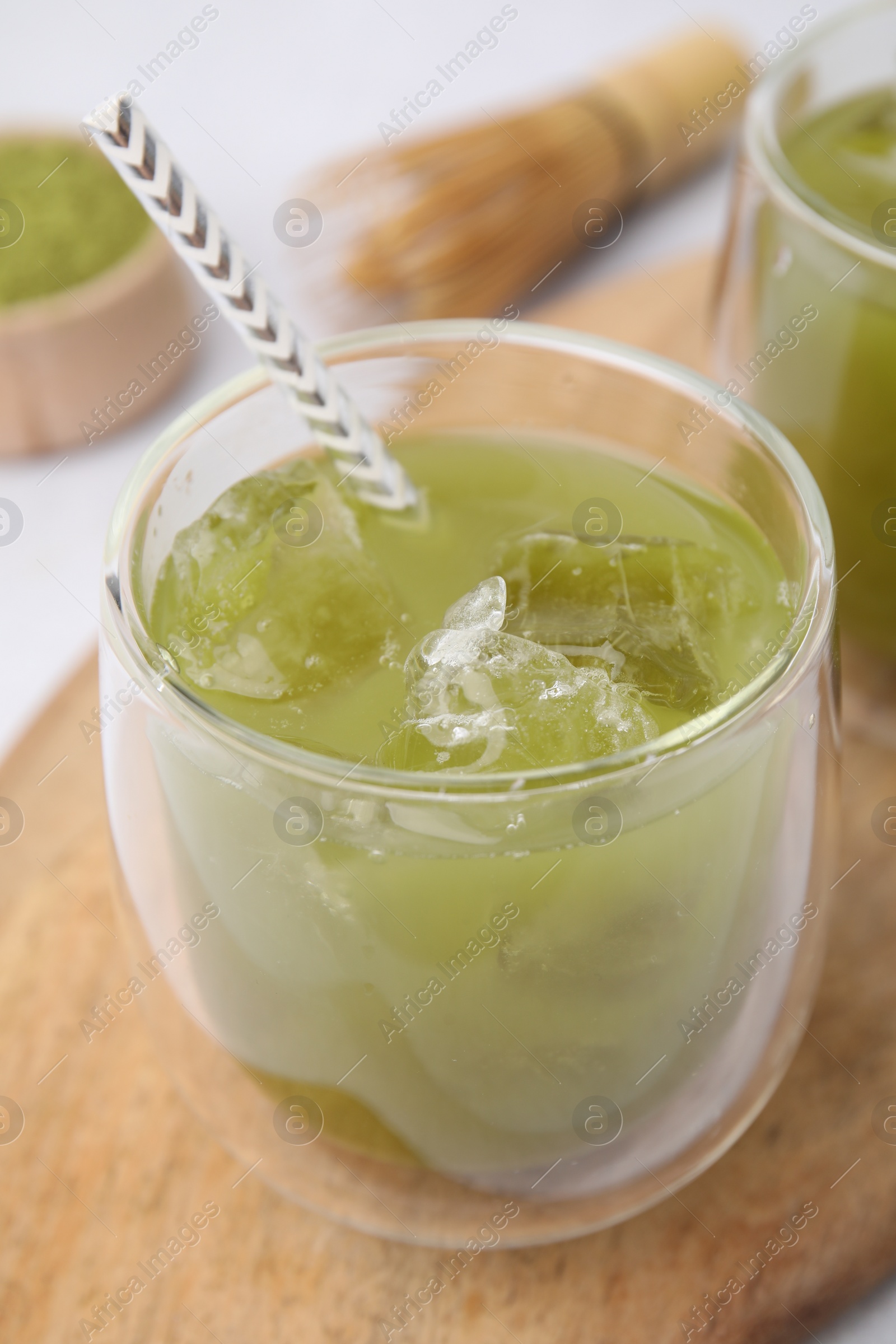 Photo of Glass of delicious iced green matcha tea on wooden board, closeup