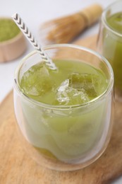 Glass of delicious iced green matcha tea on wooden board, closeup