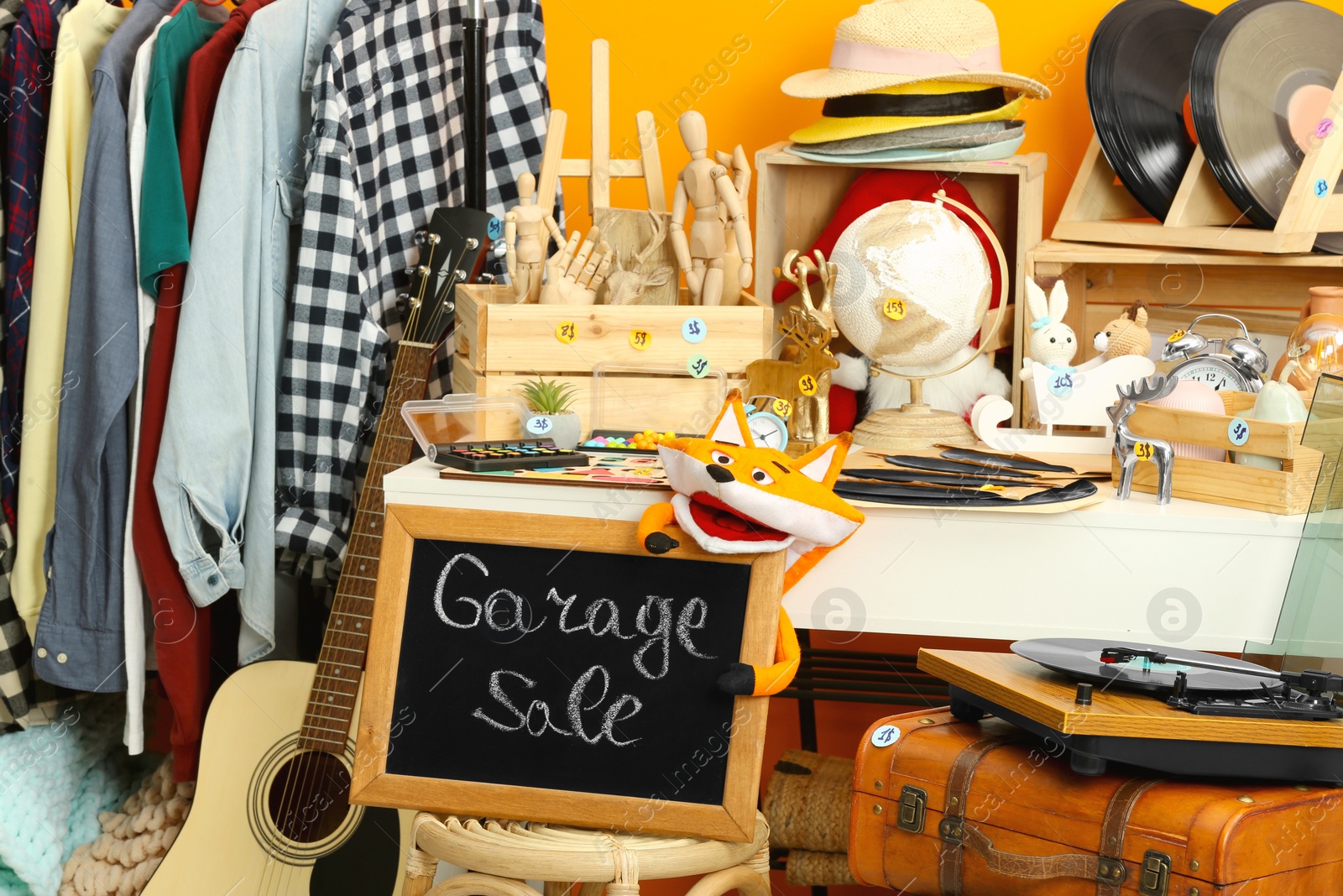 Photo of Sign Garage Sale written on blackboard near many different stuff