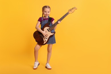 Photo of Cute girl with electric guitar on orange background