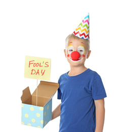 Little boy with clown makeup holding April fool's day sign on white background