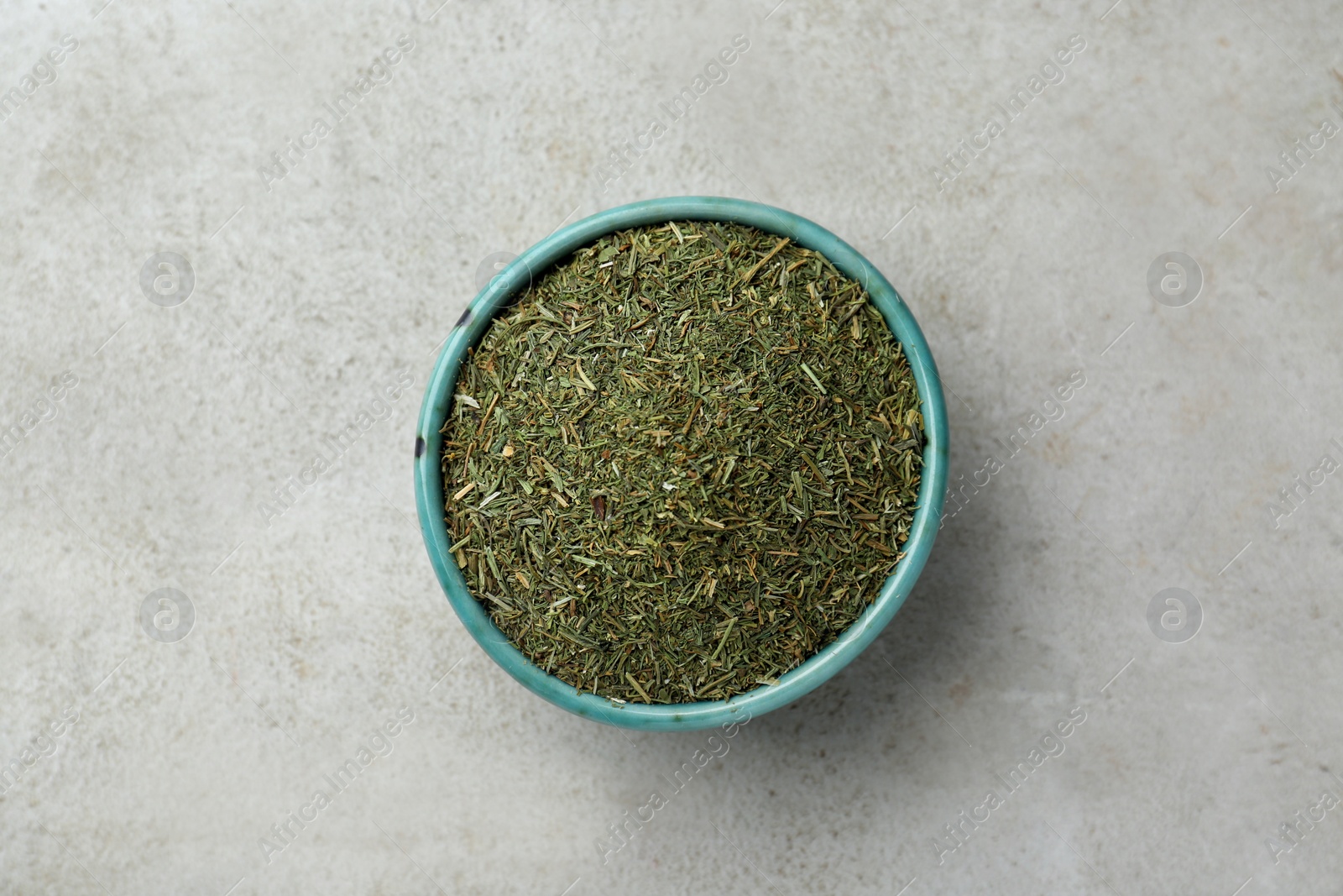 Photo of Bowl with dried dill on light grey table, top view. Space for text