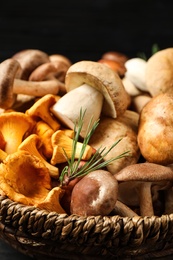 Photo of Different fresh wild mushrooms in wicker bowl, closeup