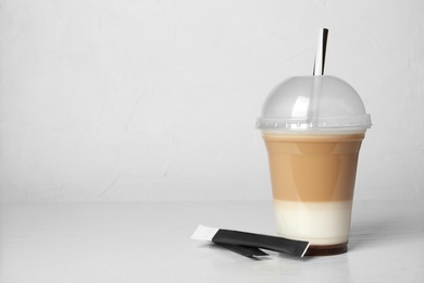 Photo of Plastic cup of tasty caramel macchiato on table, space for text