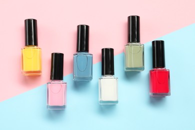 Bright nail polishes in bottles on color background, flat lay