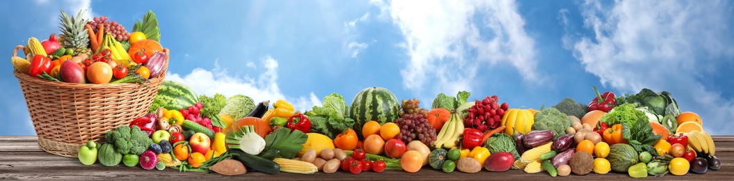 Image of Assortment of fresh organic fruits and vegetables on wooden table outdoors. Banner design