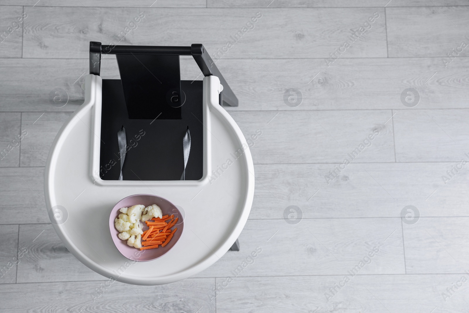 Photo of High chair with healthy baby food served on white tray indoors, top view. Space for text