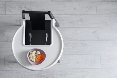 High chair with healthy baby food served on white tray indoors, top view. Space for text