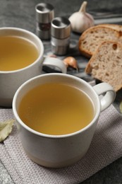 Hot delicious bouillon in cups on grey table