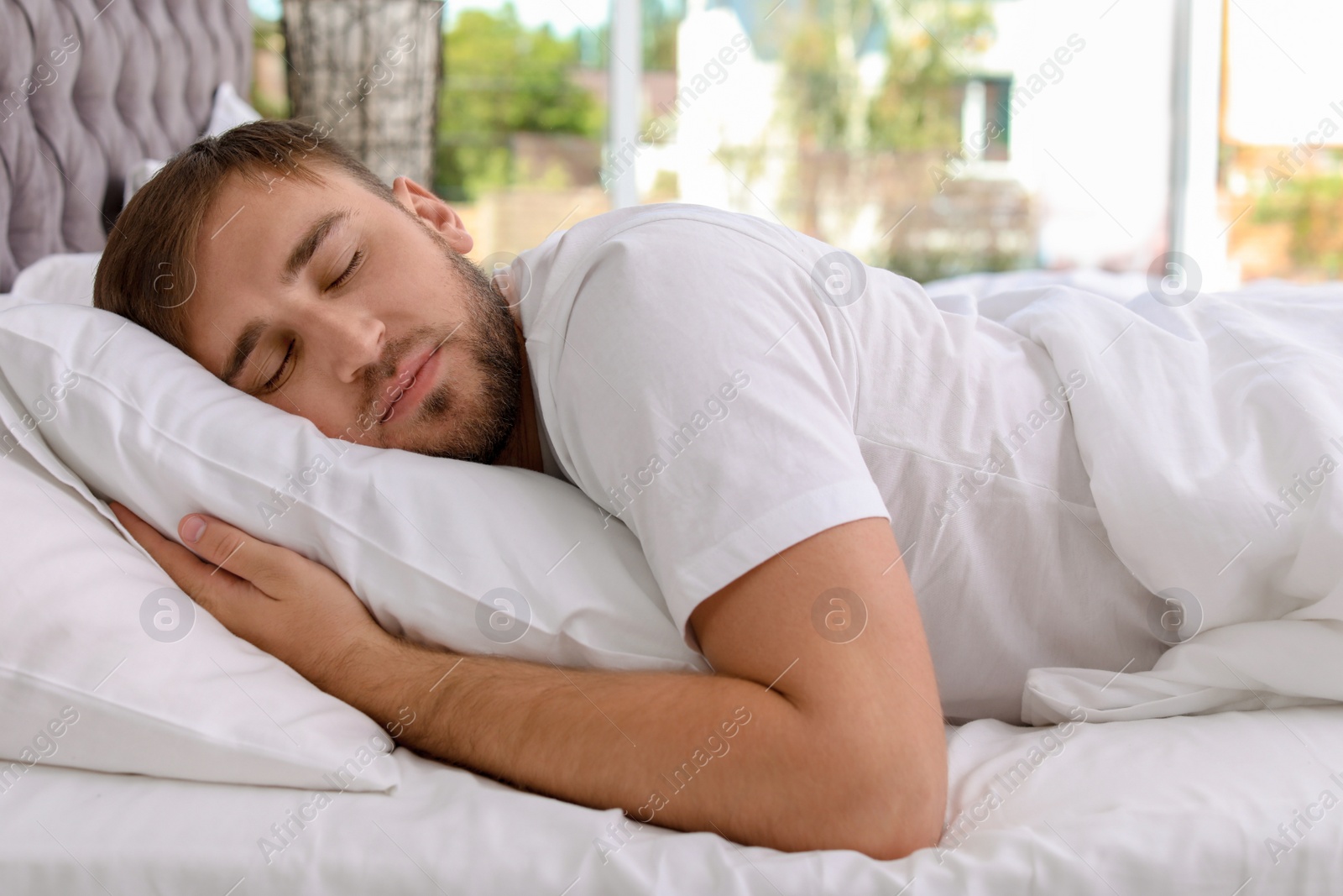 Photo of Young handsome man sleeping in bed at home. Early morning