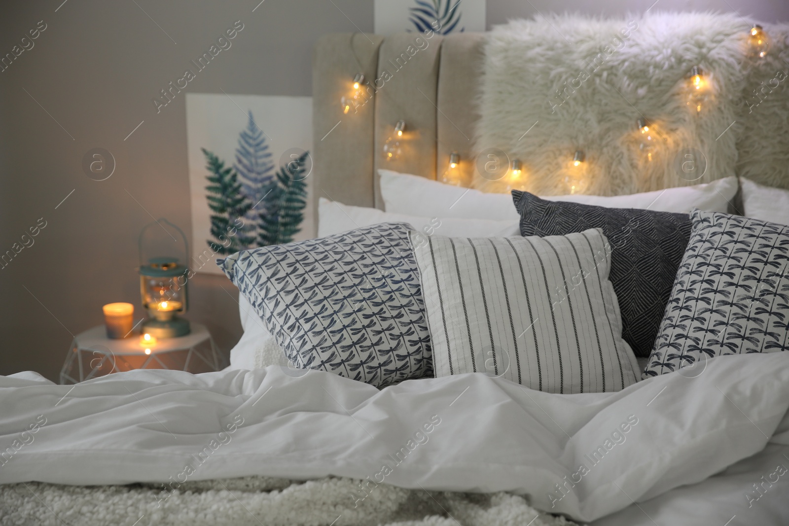 Photo of Bed with warm blanket and cushions in room. Interior design