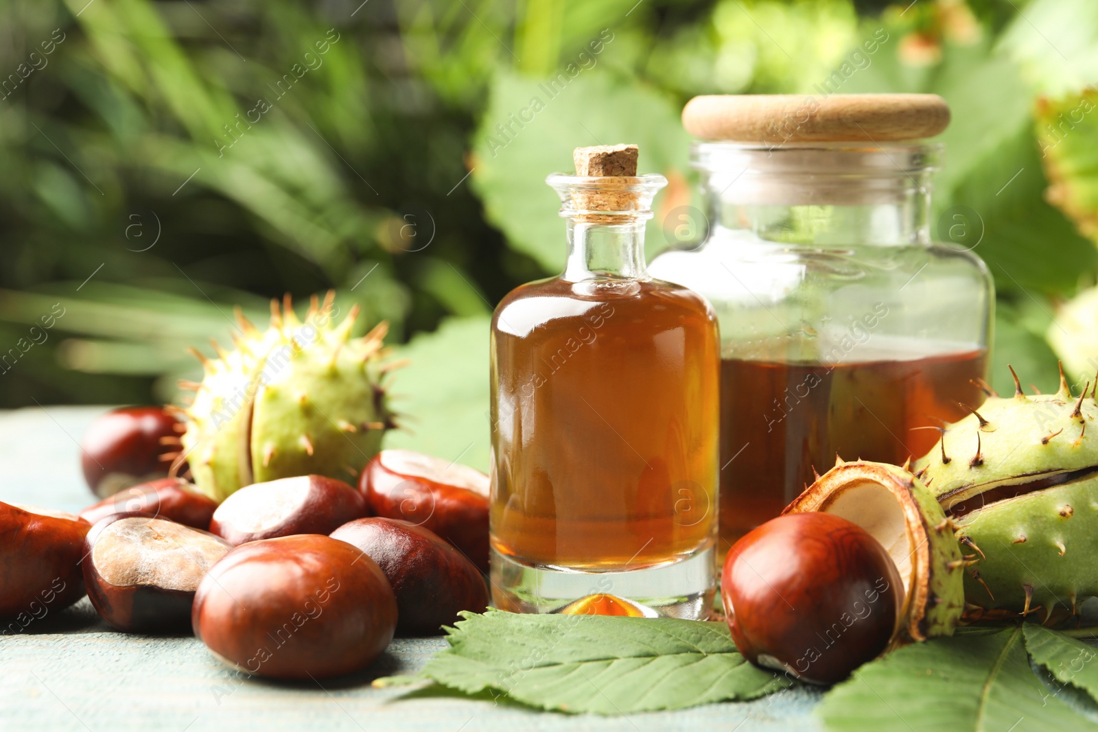 Photo of Chestnuts and essential oil on table against blurred background