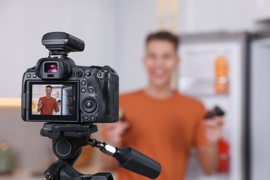 Food blogger recording video in kitchen, focus on camera