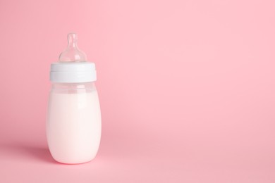 One feeding bottle with milk on pink background. Space for text