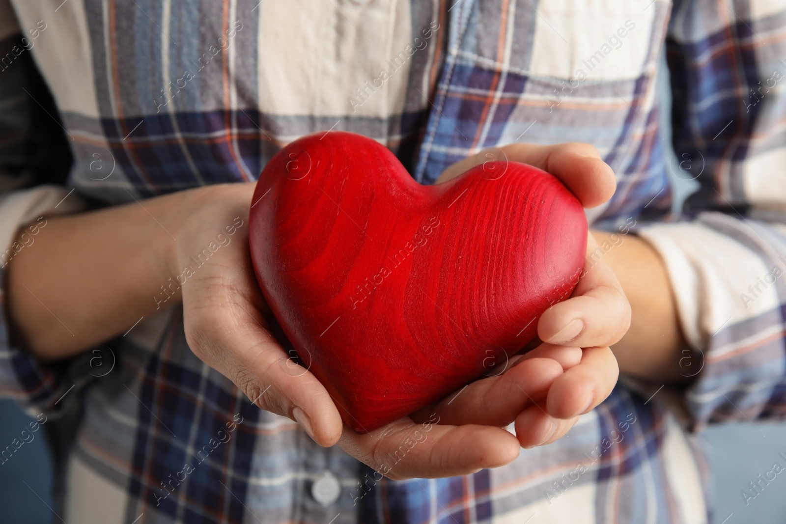 Photo of Woman holding red heart in hands, closeup. Helping and supporting concept