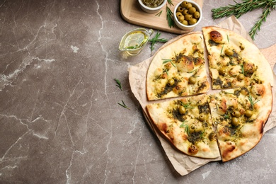 Photo of Delicious focaccia bread with green olives on marble table, flat lay. Space for text