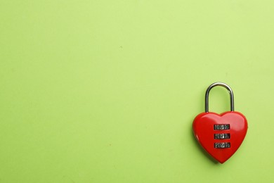 Photo of Red heart shaped combination lock on green background, top view. Space for text