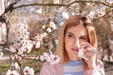 Photo of Woman suffering from seasonal allergy outdoors, space for text