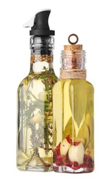 Photo of Glass bottles of cooking oil with spices and herbs on white background