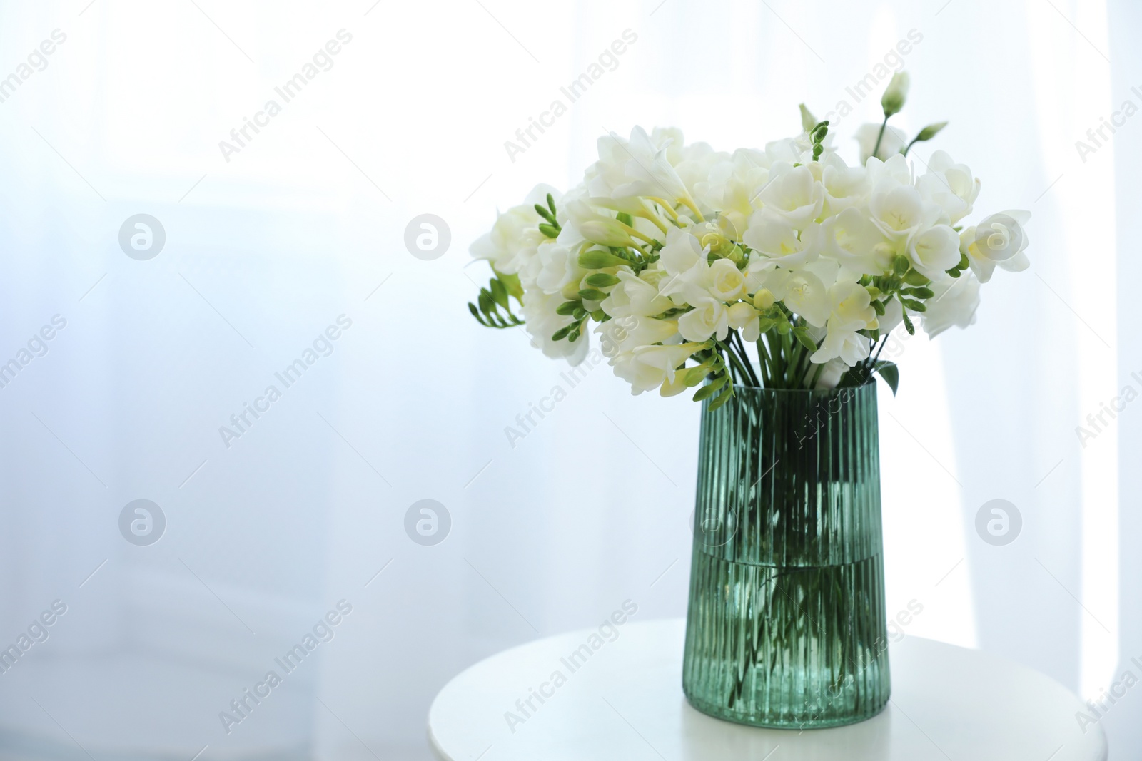 Photo of Beautiful bouquet with fresh freesia flowers on table indoors. Space for text