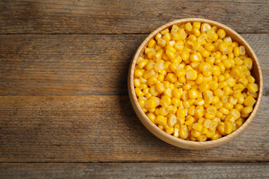 Photo of Delicious canned corn on wooden table, top view. Space for text