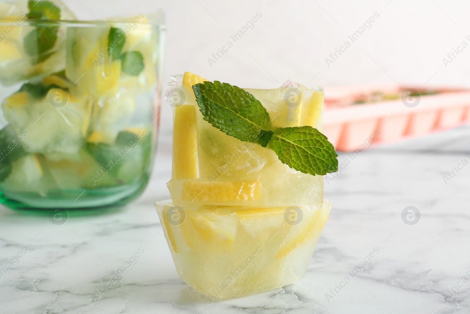 Photo of Ice cubes with mint and lemon on table, closeup