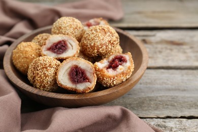 Delicious sesame balls with red bean paste on wooden table, closeup