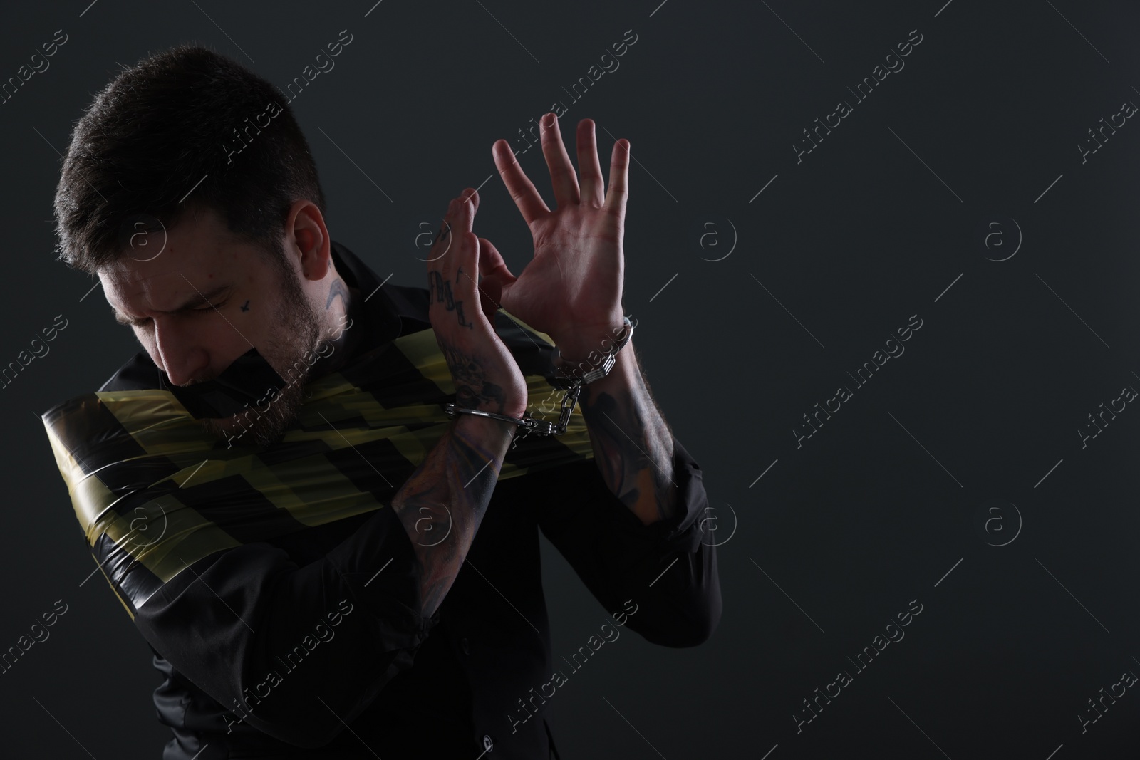 Photo of Scared man taped up and taken hostage on dark background. Space for text