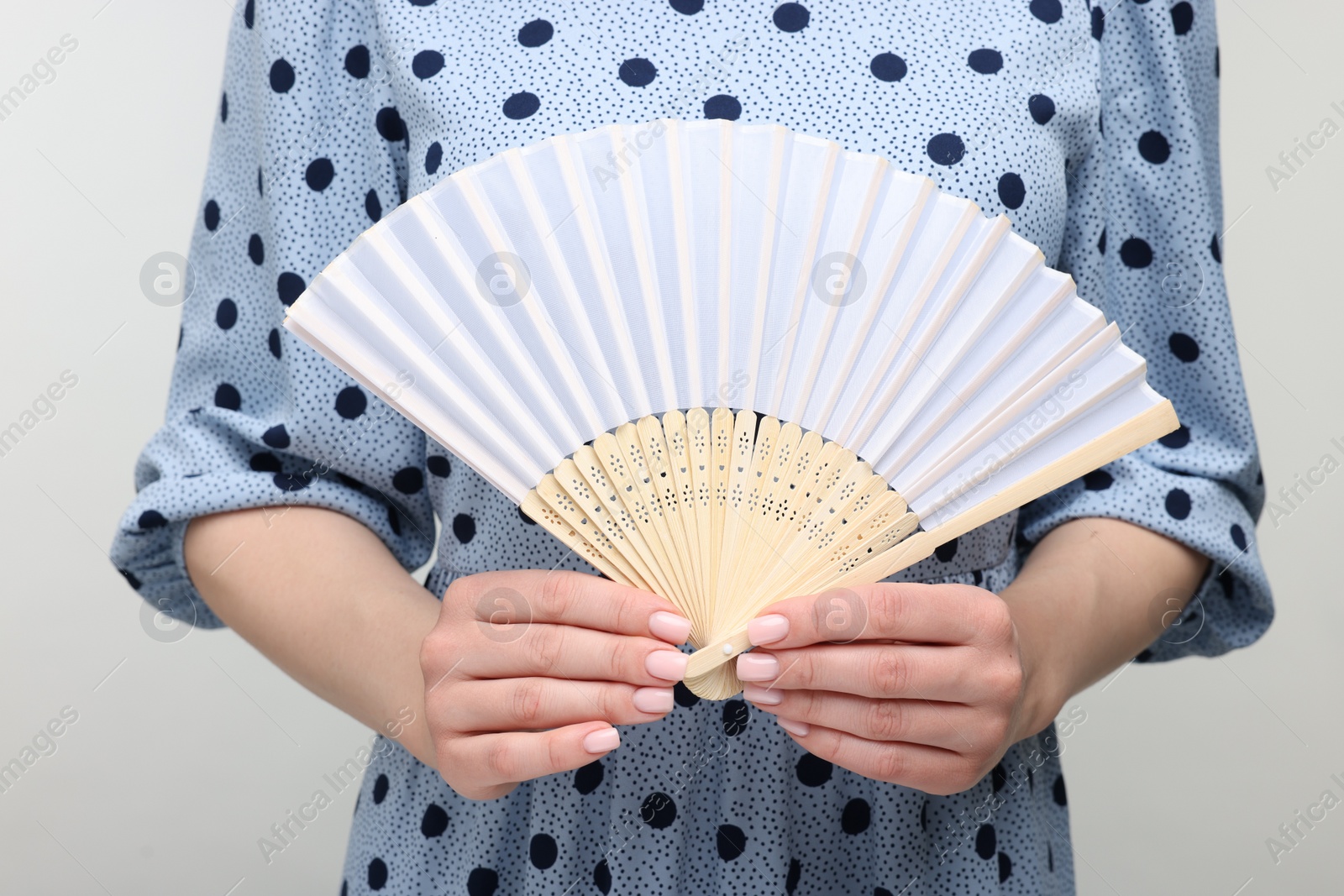 Photo of Woman with hand fan on light grey background, closeup