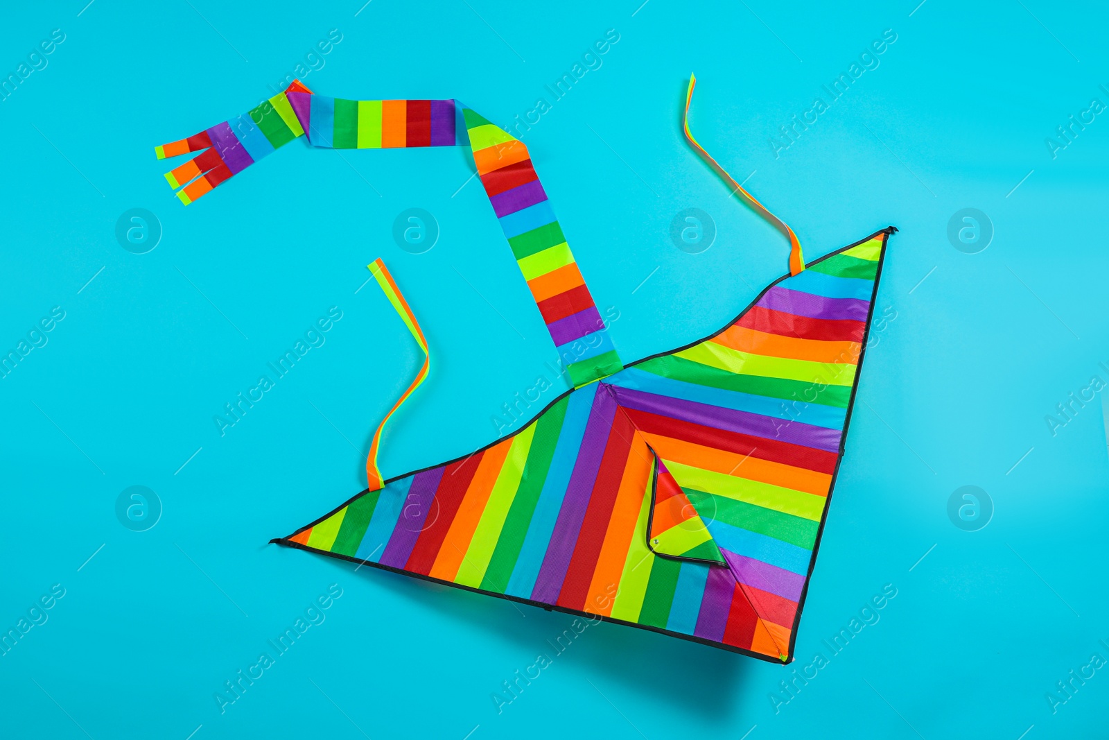 Photo of Bright rainbow kite on light blue background, top view