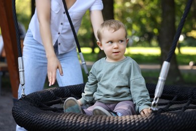Photo of Nanny and cute little boy on swing outdoors