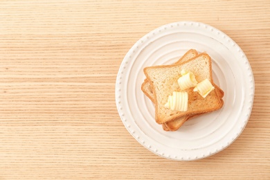 Photo of Toasted bread with butter curls on plate, top view