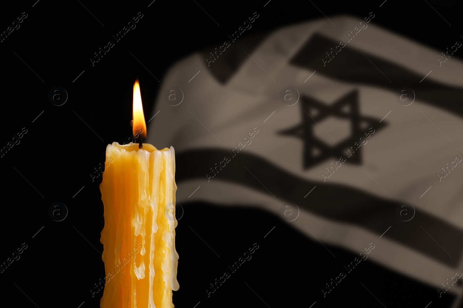 Image of Burning candle against flag of Israel on black background