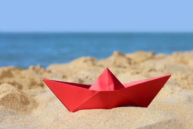 Red paper boat near sea on sunny day