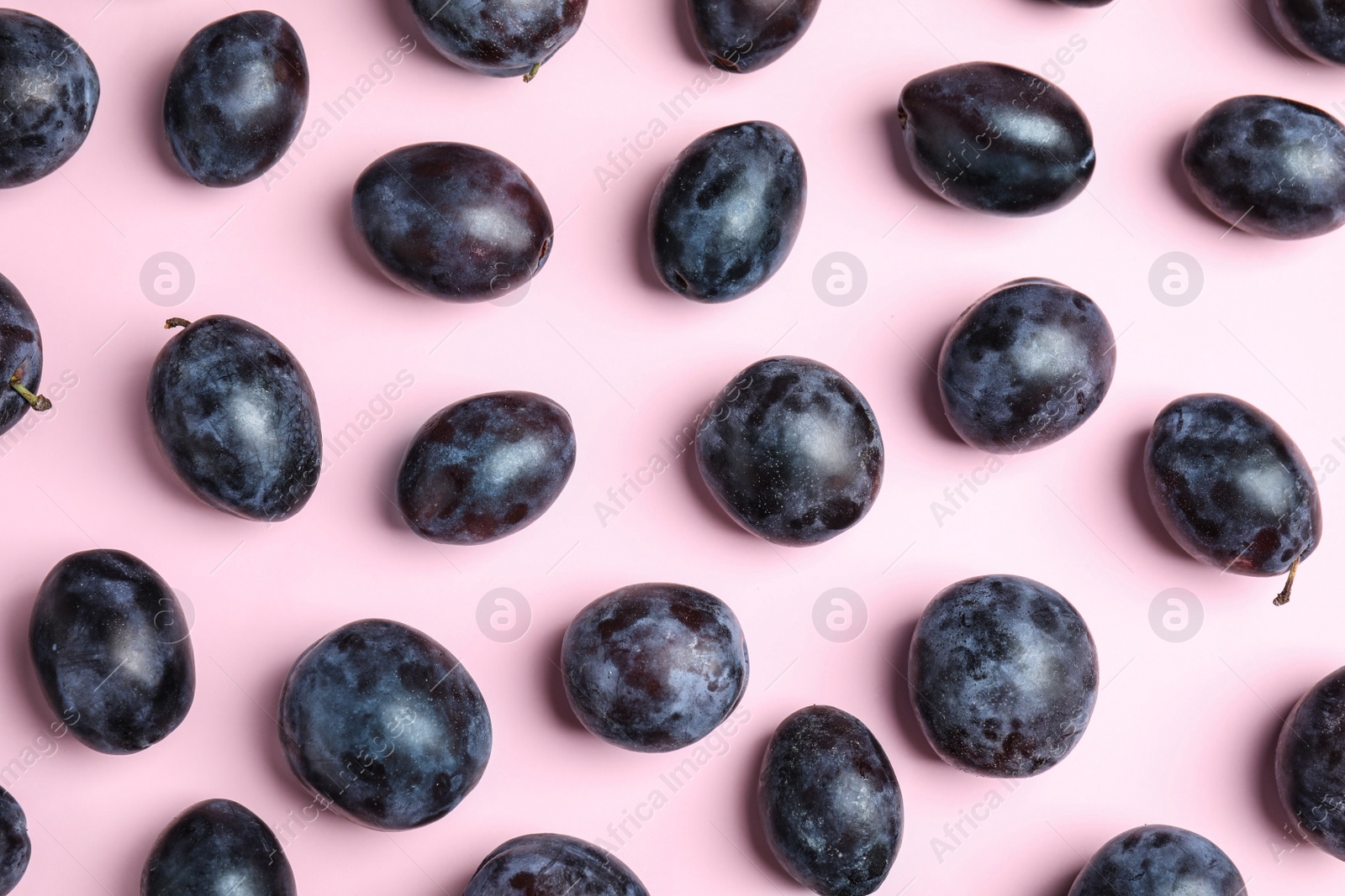 Photo of Delicious ripe plums on pink background, flat lay