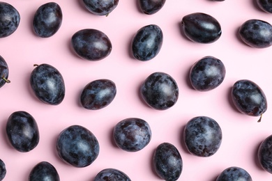 Delicious ripe plums on pink background, flat lay