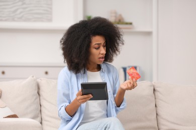 Confused woman with calculator and credit card planning budget at home. Debt problem