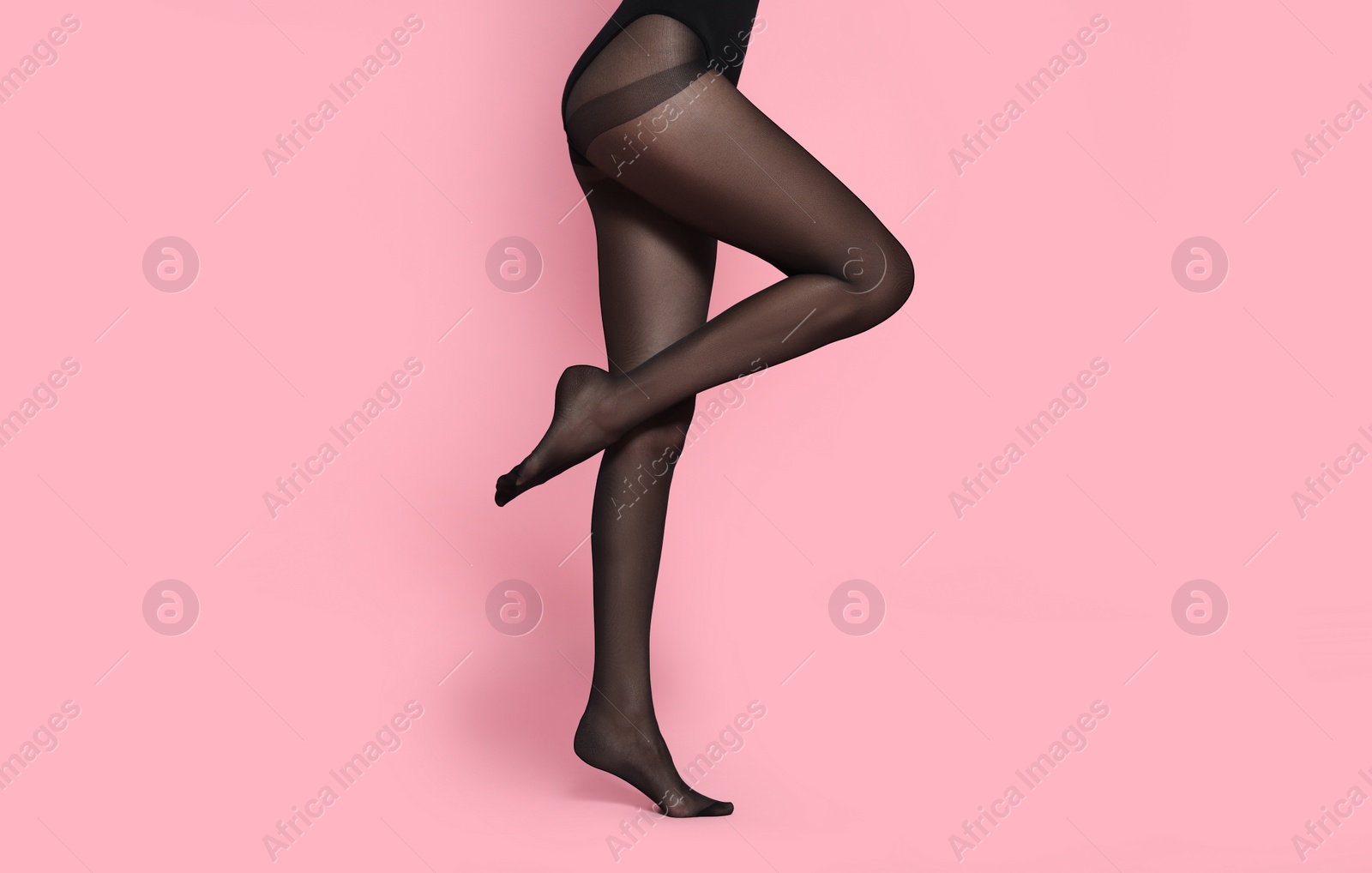 Photo of Woman wearing black tights on pink background, closeup