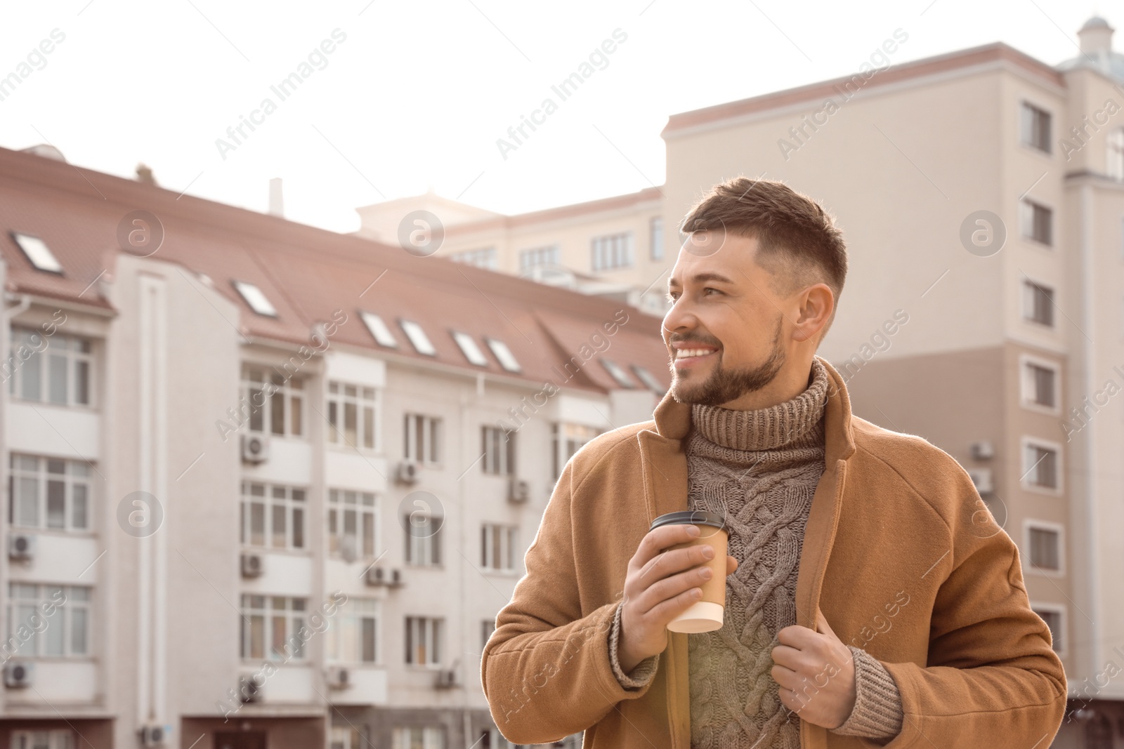 Photo of Man with cup of coffee on city street in morning