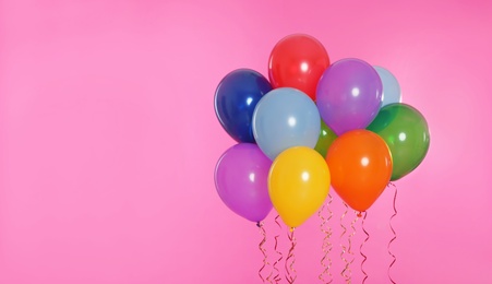 Photo of Many bright balloons floating on color background