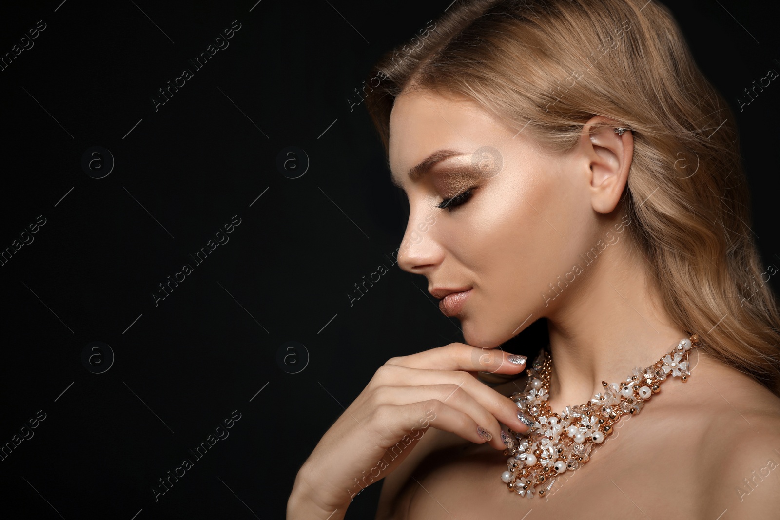 Photo of Beautiful young woman with elegant jewelry on dark background. Space for text