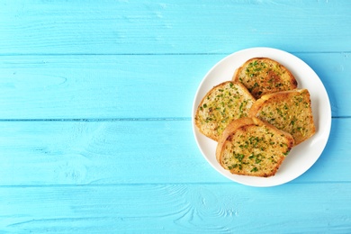 Photo of Slices of toasted bread with garlic and herbs on blue wooden table, top view. Space for text